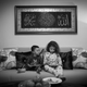 Souad and 2-year-old Hassan play on mobile devices as they sit together on the living room sofa.